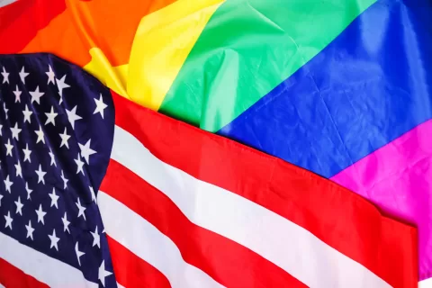 A USA flag laying on top of a rainbow pride flag