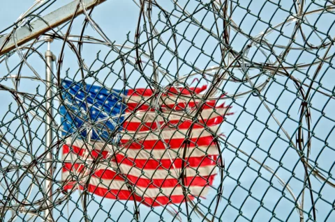 A photo of an Americal flag behind a barbed wire fence